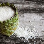 Rice,grain,in,round,basket,on,wooden,plank