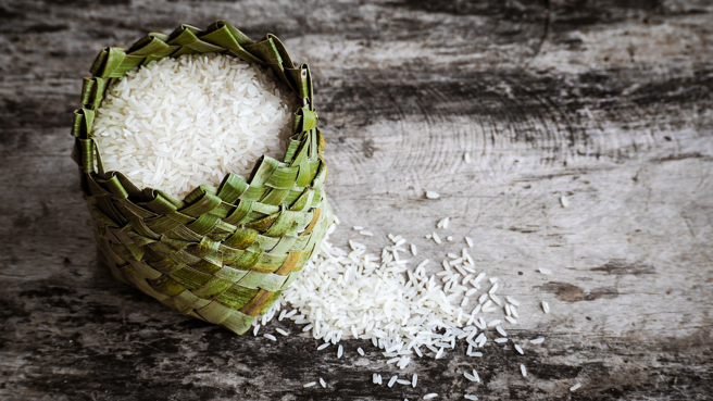 Rice,grain,in,round,basket,on,wooden,plank